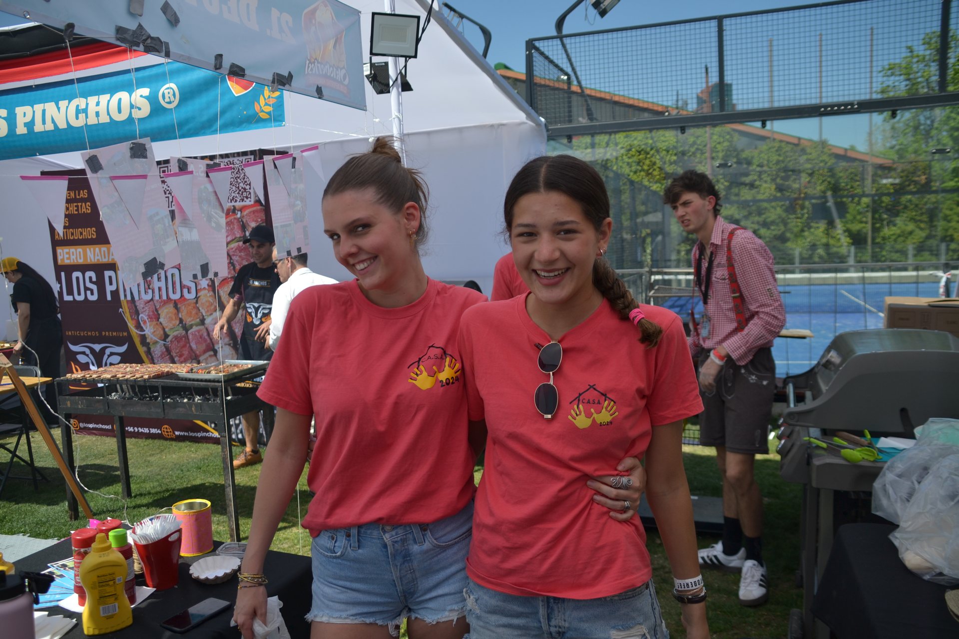 Voluntarias de polera coral en el stand del primer Oktoberfest Club Manquehue 2024