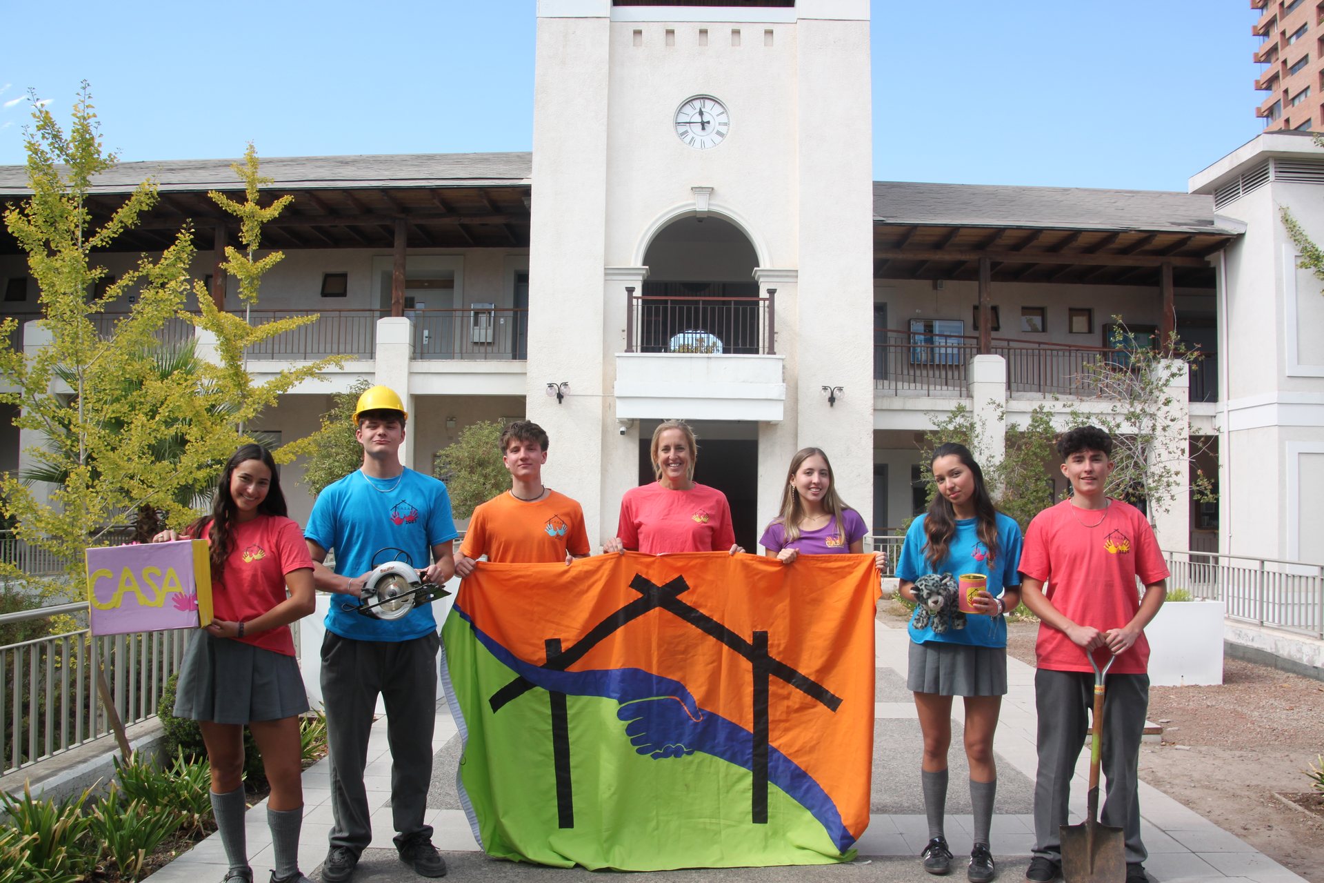 Directiva y comités 2025 frente a la torre del reloj del colegio con la bandera C.A.S.A.