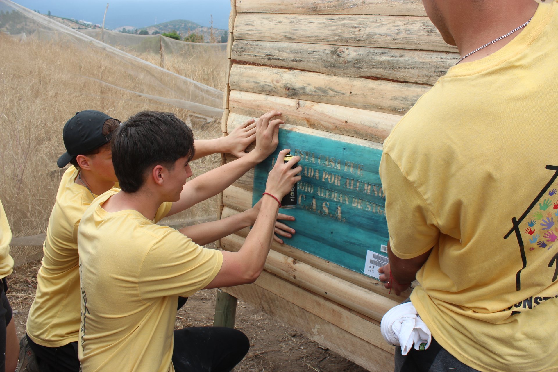 Alumnos instalando la placa stencil en un muro de tinglado, Quillota diciembre 2025