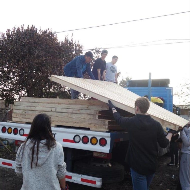 Alumnos descargan paneles de madera del camión durante las capacitaciones en Rengo, 2019