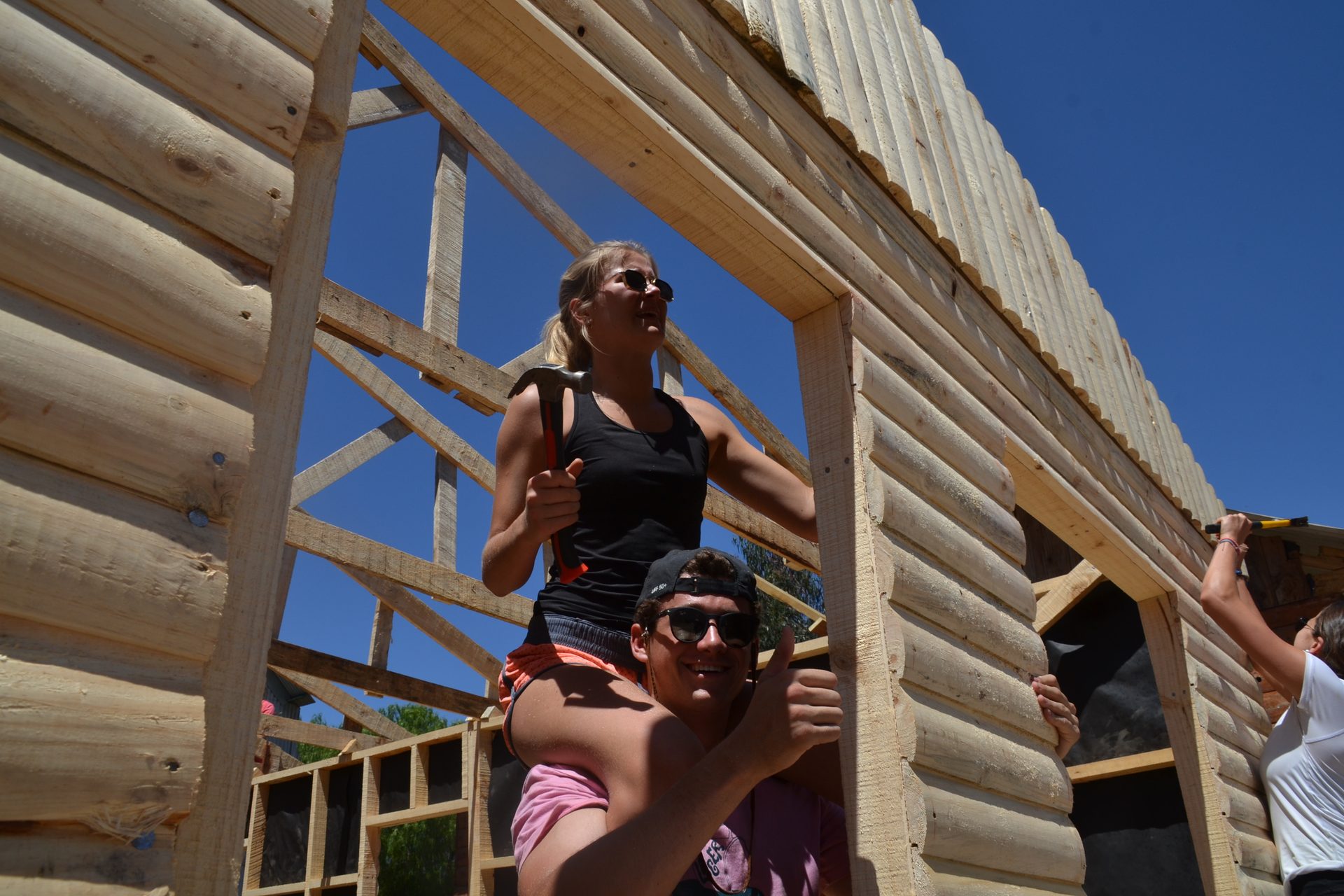 Voluntarios levantando juntos una pared de la mediagua